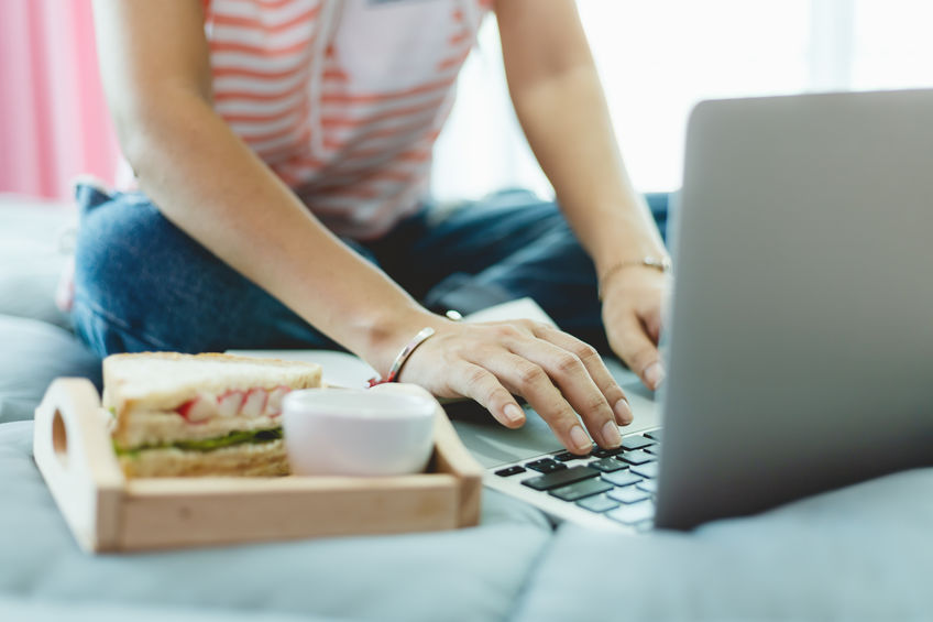 Una ragazza digita sul suo laptop mentre fa una colazione ricca e bilanciata.